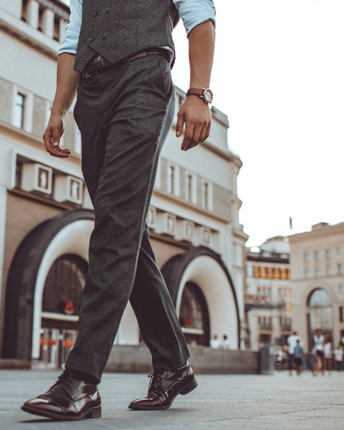 man walking in city street, cropped image of person legs  - Фото, изображение