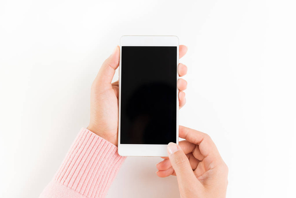 Femme main tenant smartphone téléphone portable blanc sur fond de table blanche
. - Photo, image