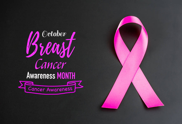 乳がん啓発月間キャンペーンをサポートするための黒い背景にピンクのリボン. - 写真・画像