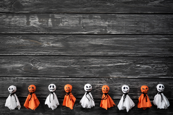Vista superior de manualidades de Halloween, fantasma de papel blanco y naranja sobre fondo de madera blanco y negro con espacio de copia para texto. concepto de Halloween
. - Foto, Imagen