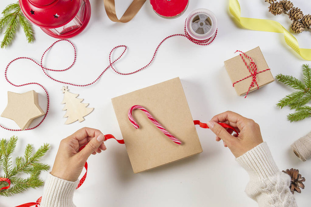 Weihnachtsgeschenkverpackung. Frauen Hände packen Weihnachtsgeschenk-Box auf weißem Tischhintergrund - Foto, Bild