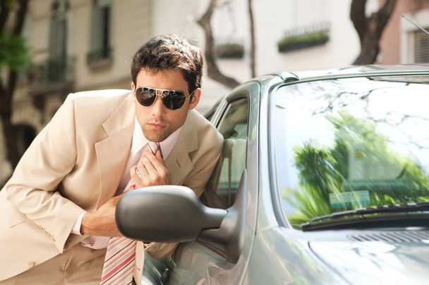 Close up view of an attractive businessman grooming himself using a car mirror outdoors - Photo, Image
