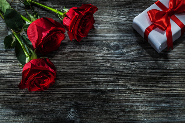 White present box bunch of red roses on wooden board. - 写真・画像