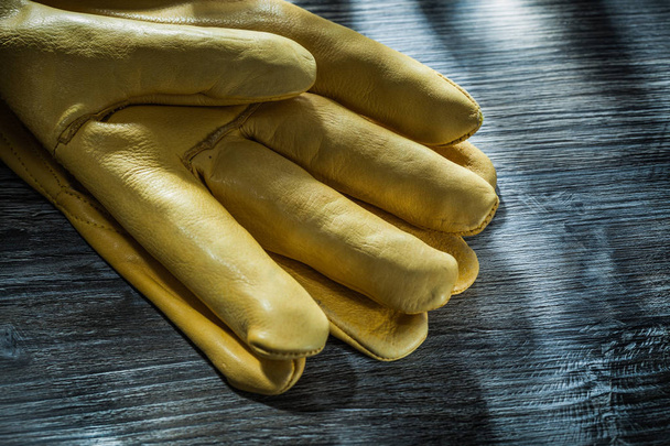 Leather safety gloves on vintage wooden board. - Фото, изображение