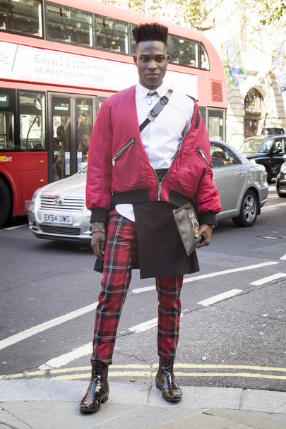 LONDON, UK- SEPTEMBER 14 2018: People on the street during the London Fashion Week. A man in a red bomber jacket, white shirt and checkered scottish trousers. - Zdjęcie, obraz
