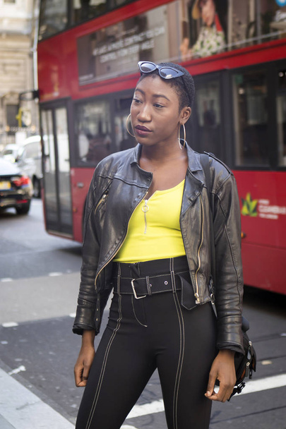 LONDON, UK- SEPTEMBER 14 2018: People on the street during the London Fashion Week. Short-haired girl in a black leather jacket and a yellow T-shirt - Фото, изображение