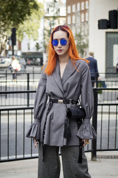 LONDON, UK- SEPTEMBER 14 2018: People on the street during the London Fashion Week. Long haired redhead girl in blue mirror sunglasses in a gray cardigan - Fotoğraf, Görsel