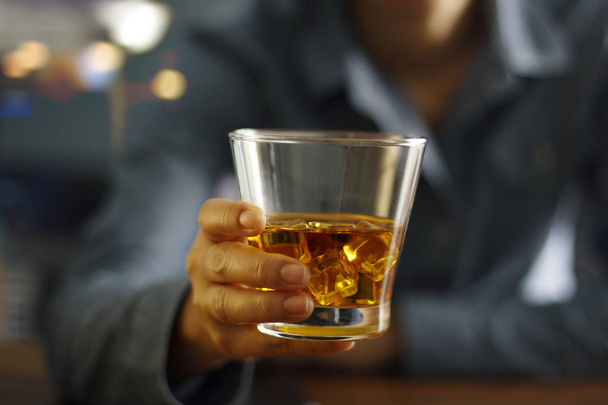 Los hombres de cerca de la celebración de whisky beben bebidas alcohólicas en el mostrador del bar en el fondo del pub
. - Foto, imagen