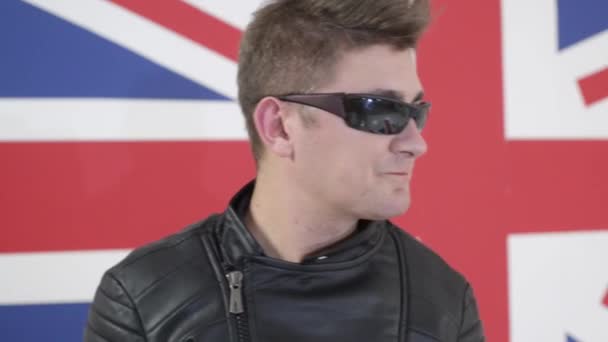 Attracitve erkek modern saç kesimi ve motosiklet ceket içinde güneş gözlüğü ile şarkı söylüyor. - Video, Çekim