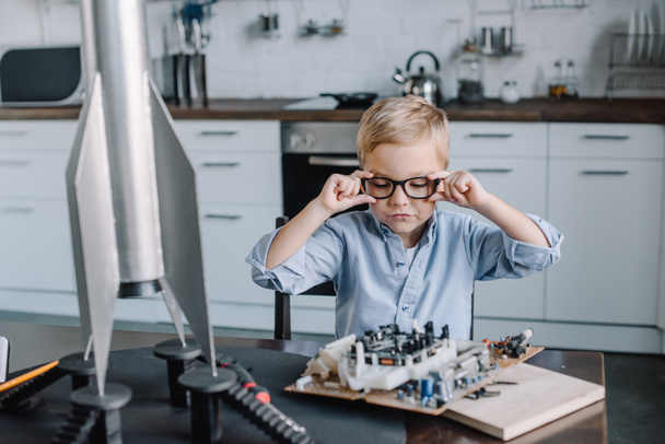 adorable boy touching glasses and looking at circuit board in kitchen on weekend - Foto, immagini