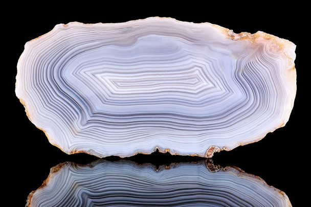 Amazing Banded Agate Crystal cross section cut isolated on black background with reflection. Natural light translucent agate crystal surface, Gray abstract structure slice mineral stone macro closeup - Photo, Image