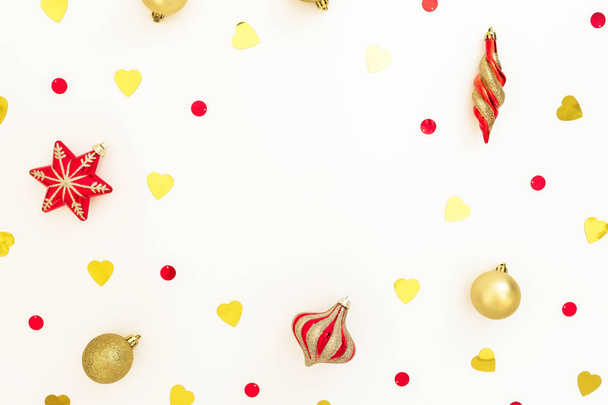 Christmas frame composition. Christmas golden and red decorations with confetti on white background. Flat lay, top view, copy space - Foto, afbeelding