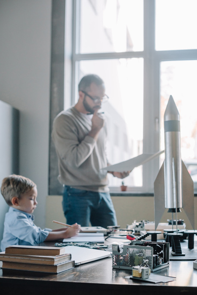 pensive father and son modeling rocket at home - Photo, Image