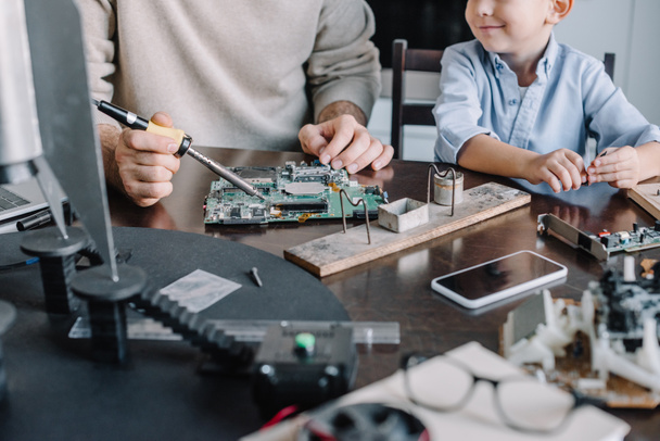 cropped image of father and son soldering circuit board with soldering iron at home - Photo, Image