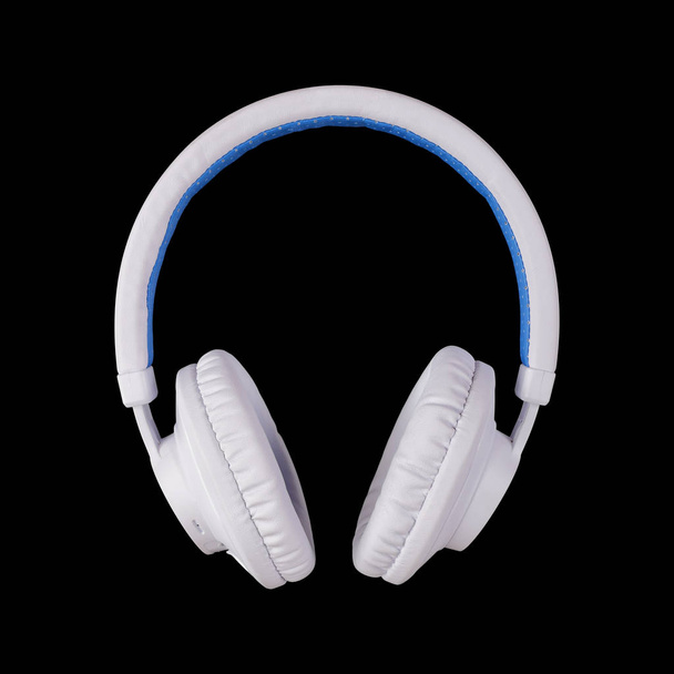 Muziekmateriaal - witte blauwe draadloze hoofdtelefoon op een zwarte achtergrond. - Foto, afbeelding