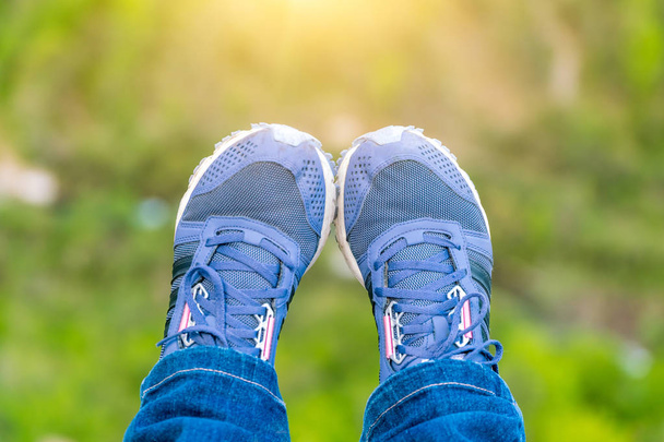 Benen in jeans en sneakers in het zonlicht - Foto, afbeelding