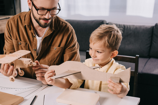 happy father and son modeling toy planes together at home - Photo, Image