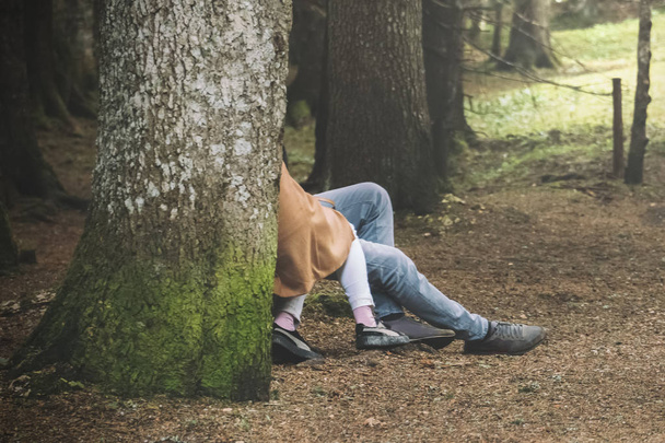 Loving couple embracing behind a tree trunk in the forest - Foto, Bild
