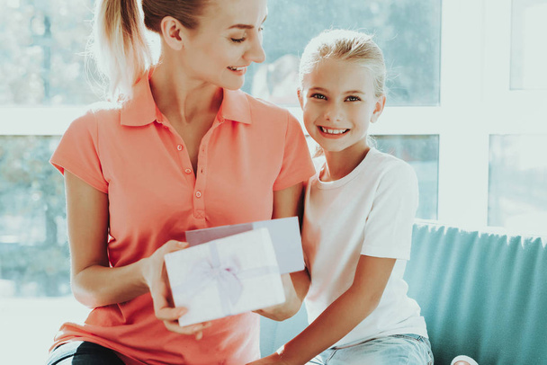 Little Daughter Is Giving A Present Box To Mum. Family Relationship Concept. Active Holiday. Beautiful Moment. Postcard To Parent. Happy Childhood. Celebrating Together. Gift Ribbon. - Foto, imagen