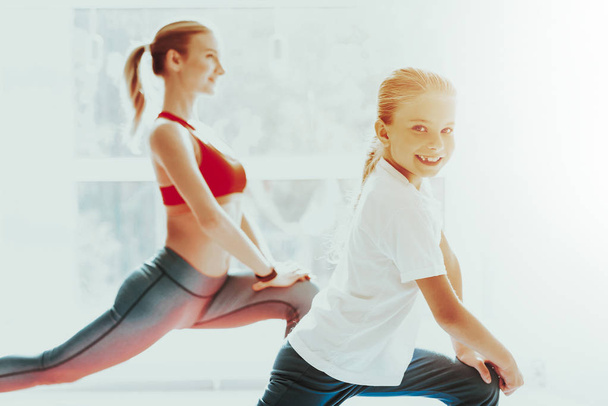 Mum And Daughter Legs Stretching At Yoga Training. Active Lifestyle. Relaxing Together. Doing Fitness At Home. Holiday Leisure. Body Balance. Sport Exercise. Hands On Knees. Sunny Day. - Photo, Image