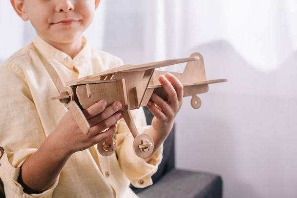 ritagliato colpo di ragazzino in possesso di aereo giocattolo in legno a casa
 - Foto, immagini