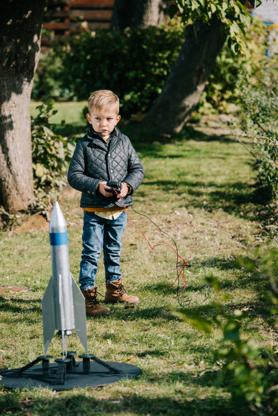 lindo niño pequeño lanzamiento modelo cohete al aire libre
  - Foto, Imagen
