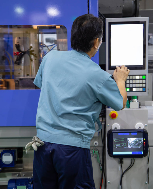 Работник эксплуатирует промышленные машины для литья пластмасс
 - Фото, изображение