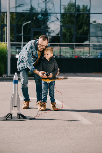 glücklicher Vater und Sohn starten Modellrakete im Freien  - Foto, Bild