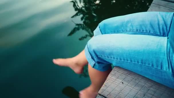 A young woman relaxes near a lake - Materiał filmowy, wideo