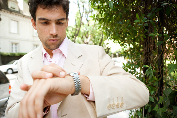 młody atrakcyjny biznesmen, patrząc w tym czasie jego zegarek - Zdjęcie, obraz