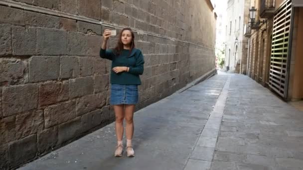 Jovencita de pie en la calle europea y tomando una foto de ella
 - Imágenes, Vídeo