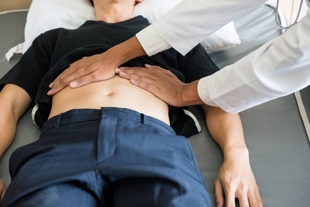 医師は、病院のベッドの上のアジアの男性患者の胃をチェックします。健康・医療サービス. - 写真・画像