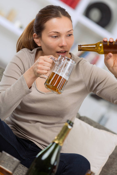 drunk young on sofa with bottle of beer in hand - Photo, image