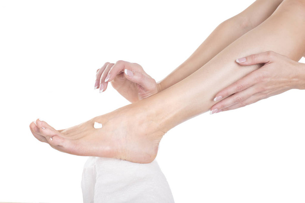 Женщина намазывает крем на босые ноги
 - Фото, изображение