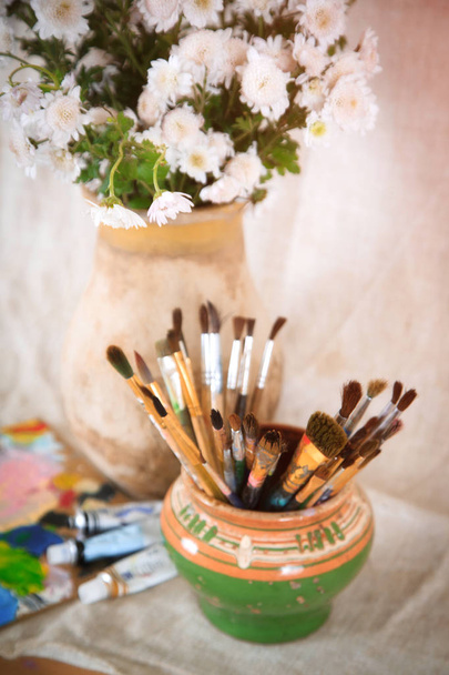 Bodegón con flores y pinceles en una olla vieja, estilo retro
 - Foto, Imagen