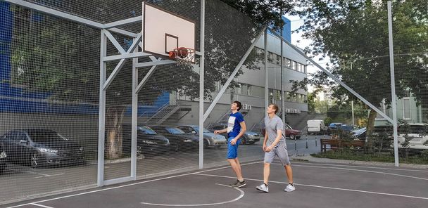 two young white men play basketball at outdoor court - Photo, Image
