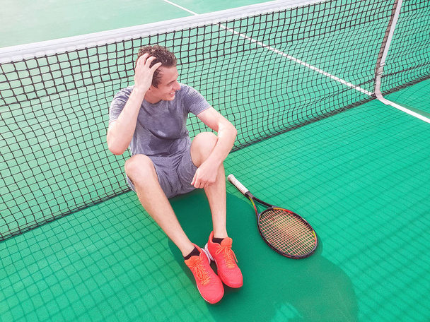 Yerde oturan erkek tenisçi - Fotoğraf, Görsel