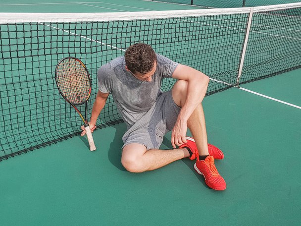 Male tennis player sitting on the ground - Φωτογραφία, εικόνα
