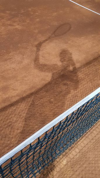 テニスコートでテニス選手の影が - 写真・画像