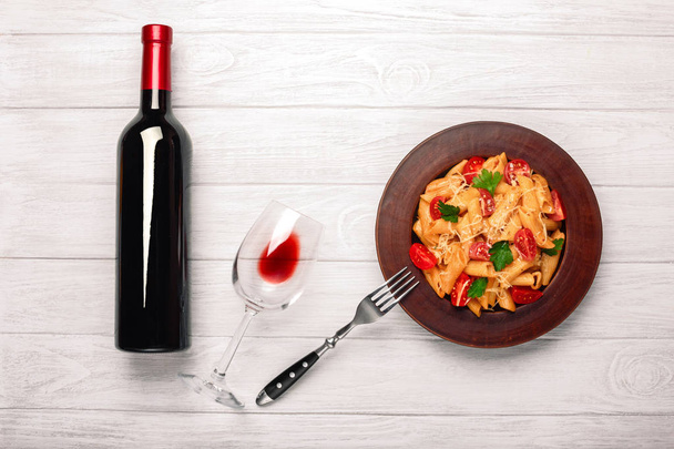 Pasta met kaas, cherry tomaat, wijnglas en fles wijn op witte houten planken, bovenaanzicht. - Foto, afbeelding