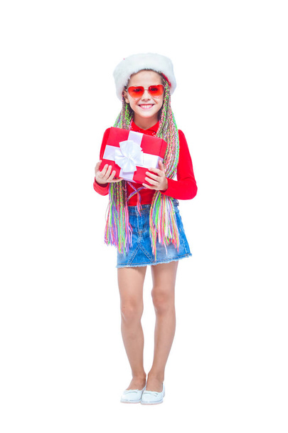 Girl in Santas hat. Portrait of little cute girl holding box of Christmas present, Small girl hug her gift with happy and fun expression isolated on white background. Holiday gift - Fotografie, Obrázek