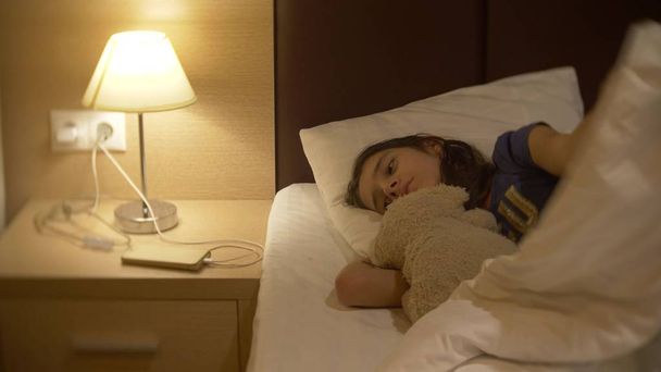 Cute little girl in her room at night, lying on the bed - Foto, Bild