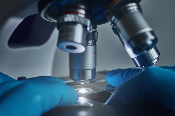 Tutkijan kädet näytteen liukumäki mikroskoopilla lähikuva laukaus laboratoriossa
 - Valokuva, kuva