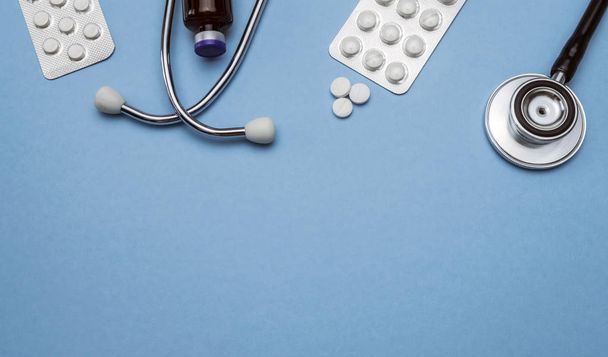 Stethoscope And tablets of pills isolated on a blue background, conceptual image - 写真・画像