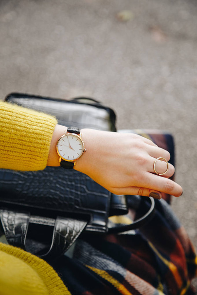 street style fashion details. close up, young fashion blogger wearing a sweater and a analog wrist watch. stylish woman checking the time on her watch. autumn/fall season. - Foto, Imagem