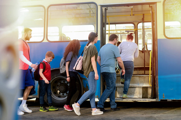 ομάδα ανθρώπων που εισέρχονται το μπλε λεωφορείο που μετέφερε τις αποσκευές τους - Φωτογραφία, εικόνα