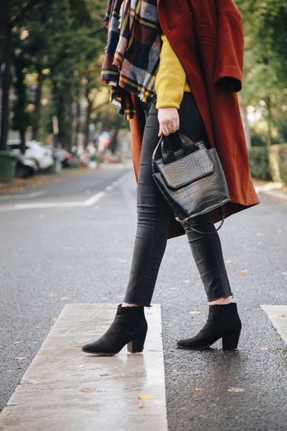 Streetstyle, aantrekkelijke vrouw het dragen van een bruin oversized jas, zwarte jeans, enkellaarzen en een krokodil effect tote tas. Fashion outfit perfect voor zonnige herfst. - Foto, afbeelding