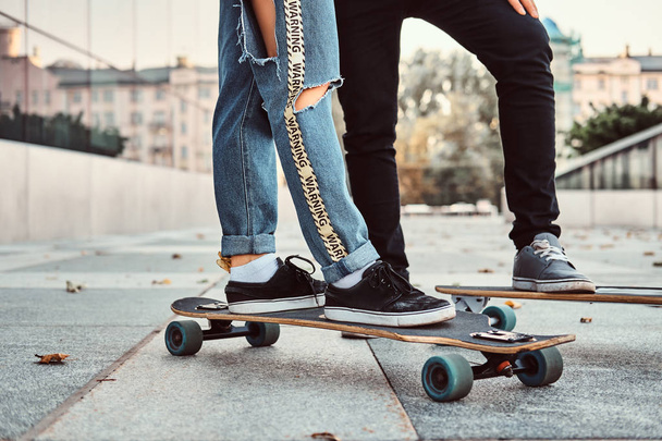 Concetto di tempo libero e sport - foto ravvicinata di una coppia di adolescenti vestiti alla moda con skateboard in strada
. - Foto, immagini