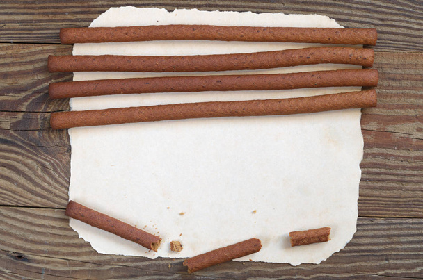 Felülnézet, rozs kenyér ragaszkodik a papír régi, fából készült háttér található. A szöveg tér - Fotó, kép