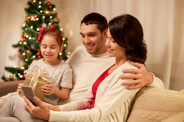 family with smartphone at home on christmas - Foto, imagen